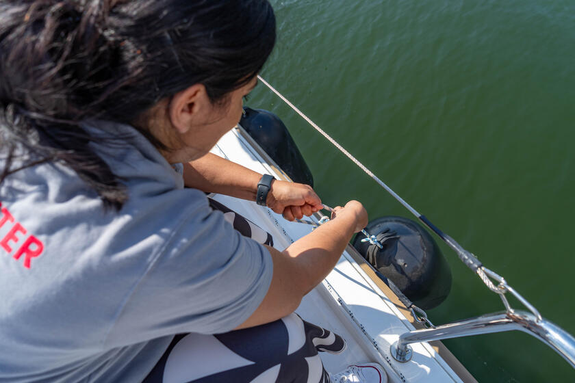 Eine Johanniterin zieht einen Fender an der Seite des Segelbootes hoch.
