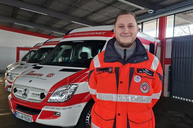 Notfallsanitäter vor Rettungswagen in Fahrzeughalle