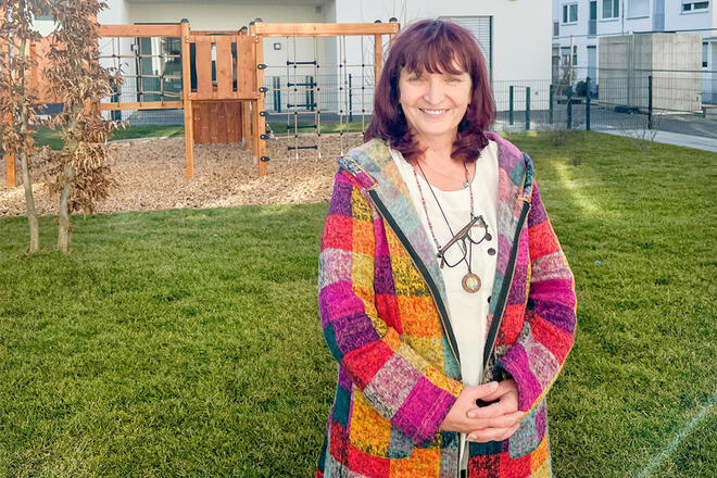 Eine Frau steht vor einem Spielplatz.